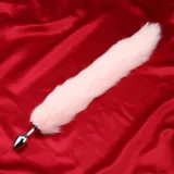 Pink faux fur tail extended diagonally on red satin with the silver-coloured plug visible at one end